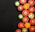 Tomatoes of different colors cut in half. Fresh and juicy vegetables on black stone background, top view Royalty Free Stock Photo