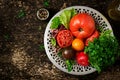 Tomatoes of different colors with green herbs in a bowl Royalty Free Stock Photo