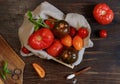 Tomatoes of different varieties in a wooden box on a linen napkin. Top view, on a dark wooden table, close-up Royalty Free Stock Photo