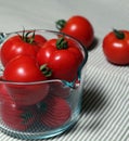 Tomatoes in a glass measuring cup with some scattered in the background