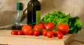 Tomatoes, green salad, olive oil bottle and vinegar transparent bottle