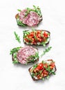 Tomatoes, italian sausage and rocket salad whole grain bread bruschetta on a light background, top view. Copy space