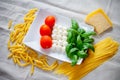 Tomatoes, mozzarella, raw pasta, parmesan cheese and green basil leaves Royalty Free Stock Photo