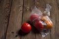 Tomatoes in a plastic bag on a natural wooden background. The image shows the harmful effects of plastic bags on food