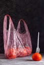 Tomatoes in a plastic bag with a white plastic fork on a dark background