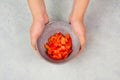 Tomatoes and red sliced pepper pieces in a bowl, prepare healthy food with paprika vegetables, holding fresh organic nutrition in Royalty Free Stock Photo