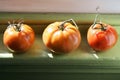 3 tomatoes sitting on a windowsill