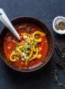 Tomatoes soup with roasted bell yellow pepper and goat cheese. Delicious vegetarian food on dark background