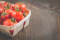 Tomatoes in a wattled basket/tomatoes in a wattled container on a dark wooden background, copyspace