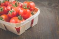 Tomatoes in a wattled basket/tomatoes in a wattled container on a dark wooden background, selective focus and copyspace