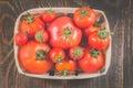 Tomatoes in a wattled basket/tomatoes in a wattled container on a dark wooden background, top view