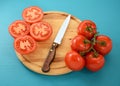 Tomatoes, whole and sliced with knife on wooden board Royalty Free Stock Photo
