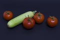 Tomatoes and zucchini on a dark background. Composition of zucchini and red tomato on a black background on a dark background. Royalty Free Stock Photo