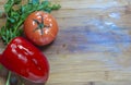 Tomatos and red sweet paprika, and leaves of parsley and fennel on a wooden board, flat lay