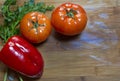 Tomatos and red sweet paprika, and leaves of parsley and fennel on a wooden board, flat lay