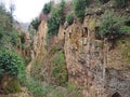 Tomb entrances in the wall of a Via Cava, an ancient Etruscan road carved through tufo cliffs in Tuscany