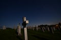 Tombstones and crosses at night in a catholic cemetery in wisconsin back-lit by the full moon under the stars