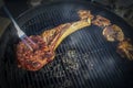 Tomohawk steak on a charcoal grill with glowing coals and smoke and a fork pressing it for doneness Royalty Free Stock Photo