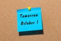 Tomorrow October. hand drawn lettering on color sticker pinned to notice cork board background