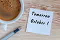 Tomorrow October - written on work notepad near morning coffee cup at informal workplace. End of september, autumn Royalty Free Stock Photo