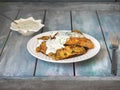 Tomorrow with potato waffles and creamy sauce in a white ceramic dish with herbs on a wooden table Royalty Free Stock Photo