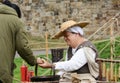 Woman dressed in Medieval clothes guides a visitor in candlemaking