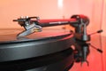 Tone arm of a modern high quality turntable record player on a vinyl analogue music LP with red backlight.