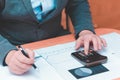 Toned Cropped image of businessman calculating invoice at desk in office