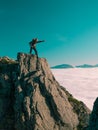 Toned image adult man with backpack stands on the edge of a cliff and screams and shows his hand into the distance against the