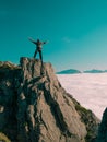 Toned image adult man with backpack stands on the edge of a cliff and screams and shows his hand into the distance against the