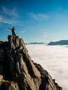 Toned image adult woman with a backpack with arms outstretched stands on the edge of a cliff and looking at the sunrise against th