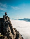 Toned image adult woman with a backpack stands on the edge of a cliff and looking at the sunrise against the blue sky