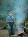 Toned image of the child sitting on the bench and playing a drum next to a burning fire Royalty Free Stock Photo