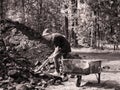 Toned image dirty little boy with a shovel in his hands which stands beside iron trolley and digging coal against the backdrop of