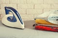 Toned image of house appliances with iron and stack of clothes on ironing board