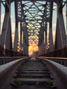 Toned image of the railway with sleepers and rail bridge on a background of multicolored sunset