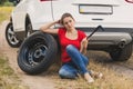 Toned image of young woman holding car wheel wrench struggling to change flat tire in field Royalty Free Stock Photo