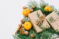 Toned instagram image wrapping rustic eco Christmas gifts with craft paper, string, tangerines and natural cypress branches on