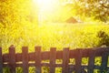 Toned nature with wooden fence, grass and old house with sunlight