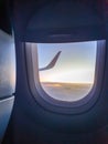 Toned image through the airplane porthole of wing in sunset light over the clouds Royalty Free Stock Photo
