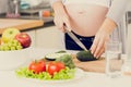 Toned photo of pregnant woman making salad on kitchen Royalty Free Stock Photo