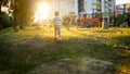 Toned image of 3 years old little boy running in park towards the sun setting down at evening Royalty Free Stock Photo