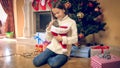 Toned image of young smiling girl caressing kitting under Christmas tree at house