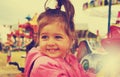 Toned portrait of happy cute smiling girl riding on carousel Royalty Free Stock Photo