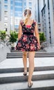 Toned rear view image of sexy young woman in short dress and ballet flats walking up the stone stairs next to high Royalty Free Stock Photo