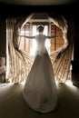 Toned shot of young bride opening curtains at hotel room