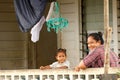 Tongan woman with a child sitting on a front porch of her house, Neiafu town, Vavau, Tonga