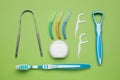 Tongue cleaners and other oral care products on light green background, flat lay Royalty Free Stock Photo