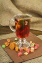 Toning ginger tea with lemon and mint. Glass cup of tea with ginger and lemon and candied fruit on a wooden background