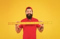 This is too big. Measuring a line. back to school. Teacher hold metric ruler yellow wall. bearded man preparing for